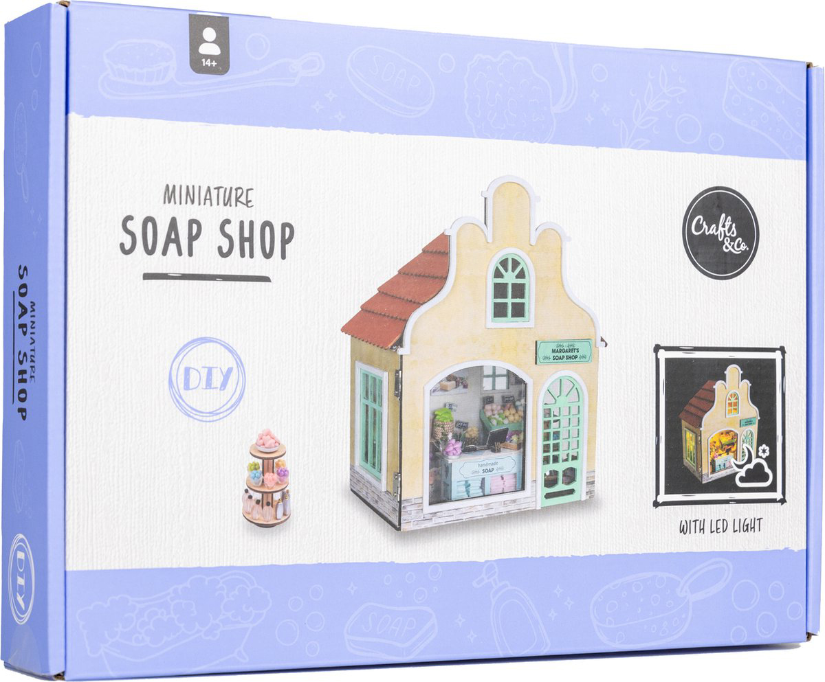 Verpackung für ein Miniatur-Seifenladen-Bausatz. Enthält ein Modell mit LED-Licht und einem kleinen Verkaufsstand.